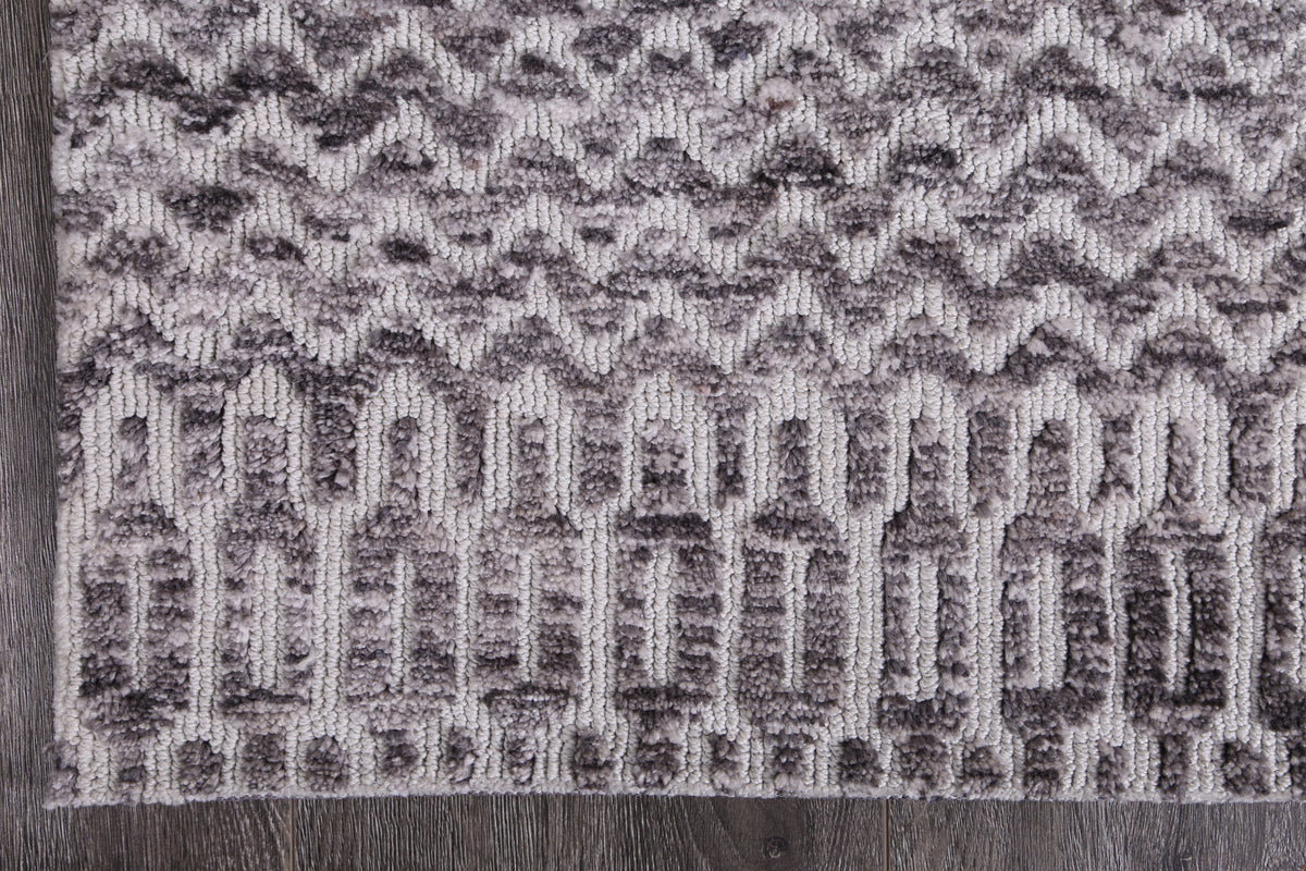 Le Canvas Kira — Grey tribal-geometric rug, corner and bound-edge detail on timber floor
